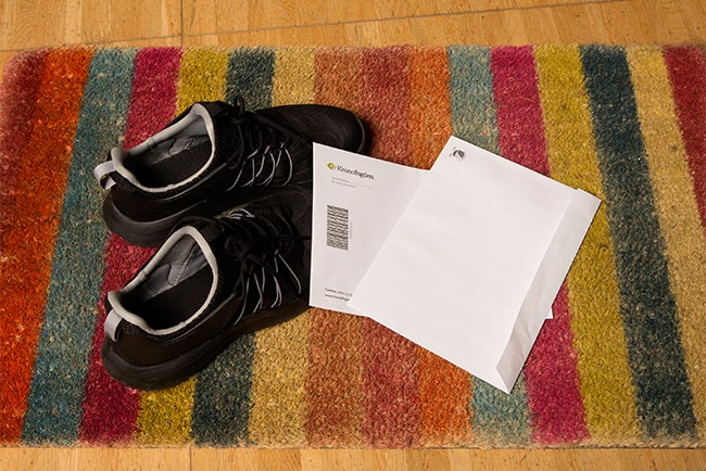 ett par skor och brev från kronofogden på en hallmatta