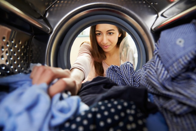 kvinna stoppar in tvätt i tvättmaskin