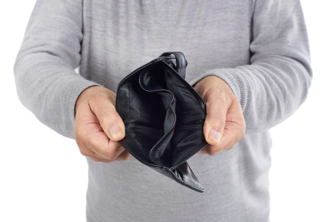 Man med grå stickad tröja håller upp en svart plånbok som är tom.