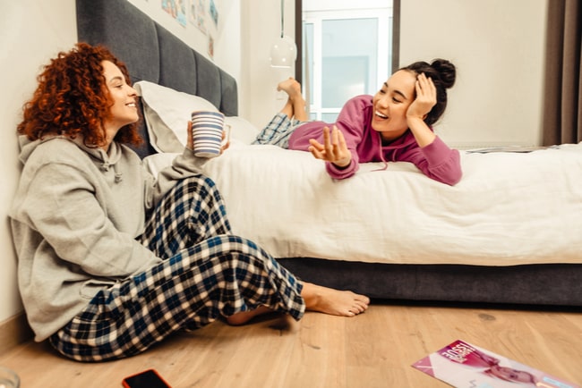 två unga kvinnor pratar i sovrum, rumskompisar